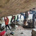 Climbers hang from rock roof