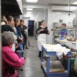 People gathered in a semi-circle watching a baking demonstration