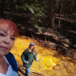 Women stand by bright yellow creek