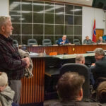 crowded hearing room with one man speaking with his arm pointed out