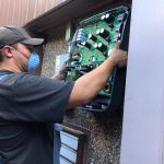 Man wearing face mask holds circuit board