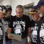 five miners wearing shirts that say Black Lung Kills gather around a notepad