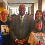 Tall man in suit with five women standing in a hallway