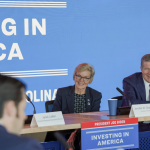 Man and woman sit at table in front of blue backdrop