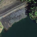 This aerial satellite photo looks down on a fissured earthen dam.